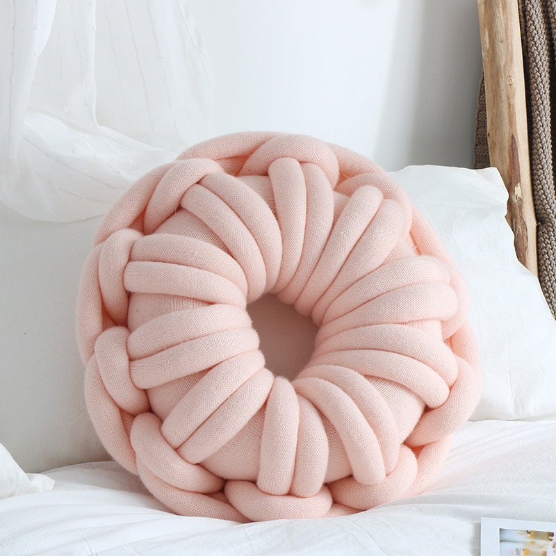 pink donut knotte cushion on a white bed