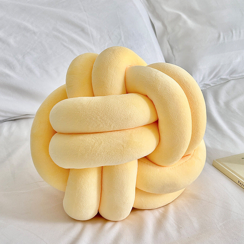 Yellow knot pillow on a white bed