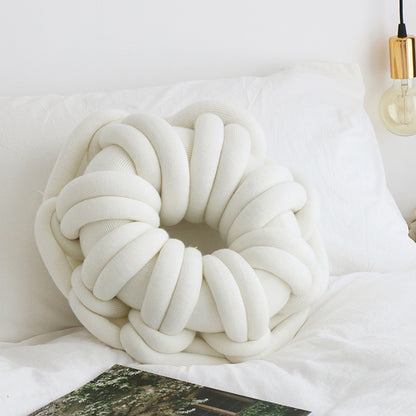 white donut knotte cushion on a white bed