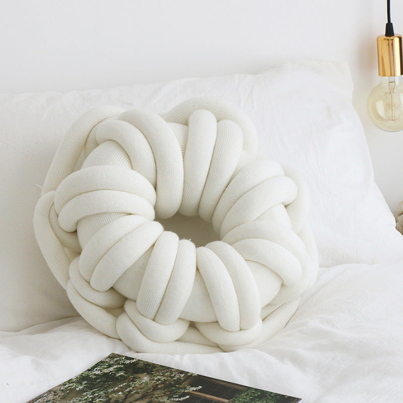 white donut knotte cushion on a white bed