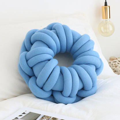 blue donut knotte cushion on a white bed