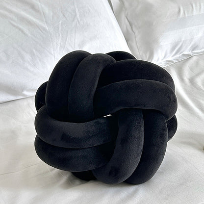 Black knot pillow on a white bed