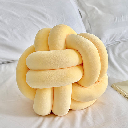 Yellow knot pillow on a white bed