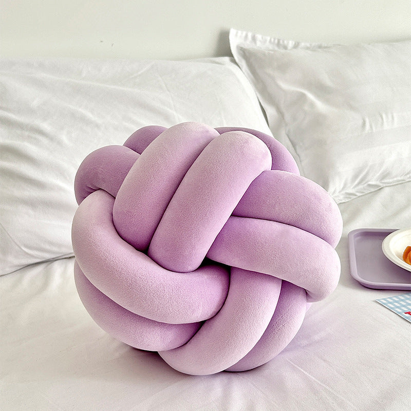 soft lavender knot pillow on a bed with white bedding