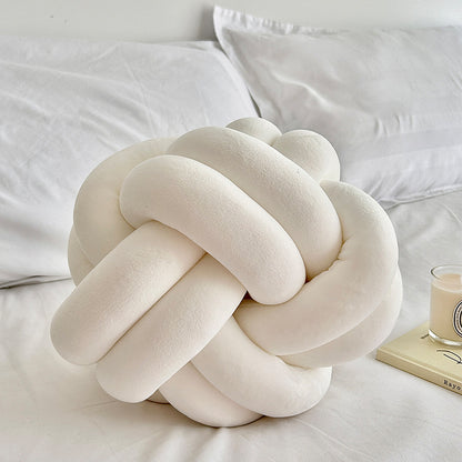 white knot pillow on a white bed