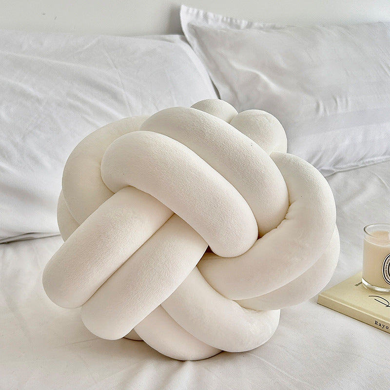 white knot pillow on a white bed